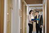 a man and a woman looking at a file while standing in a hallway in front of an office door